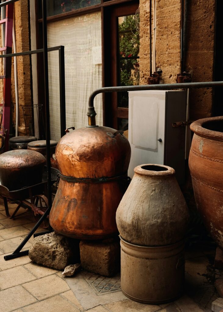An old copper still beside traditional clay pots
