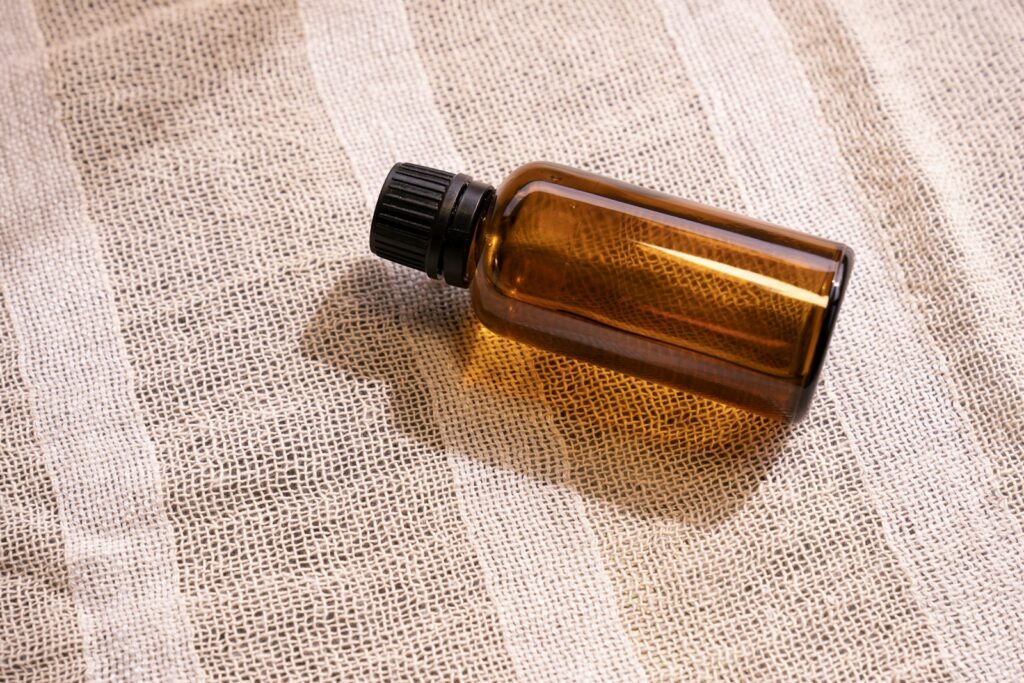 A small amber glass bottle of perfume oil resting on linen