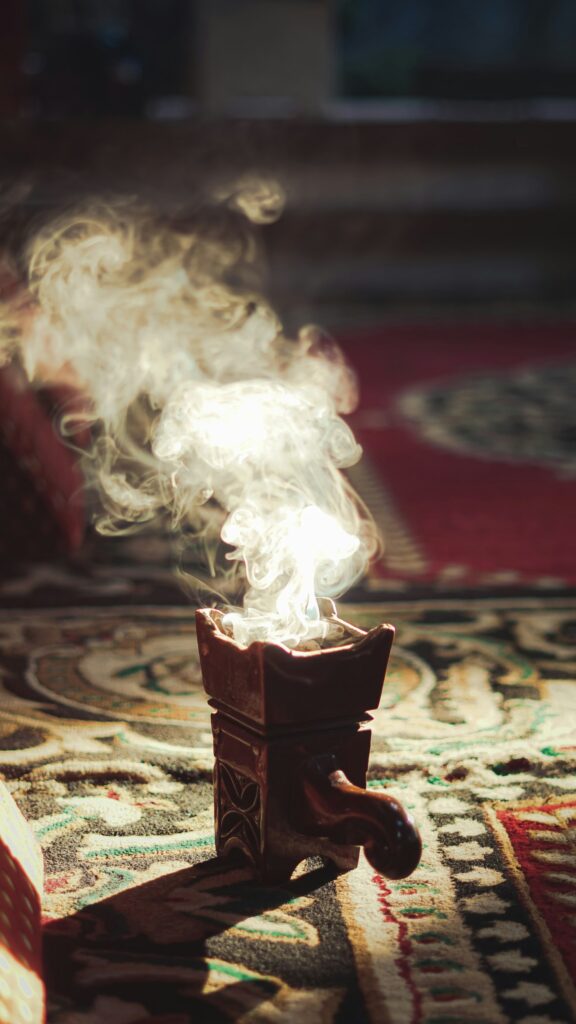 A traditional incense burner releasing fragrant smoke over a patterned rug