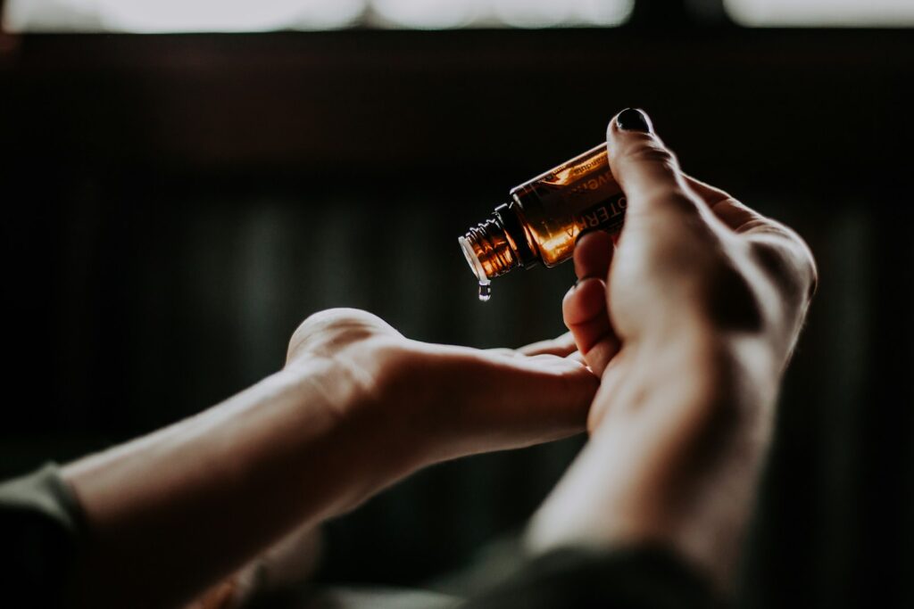 Hands applying a few drops of perfume oil to the wrist